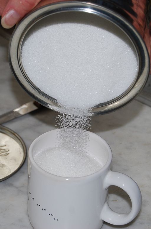 ugar being poured from a bowl to a cup.