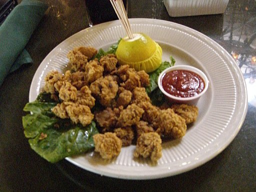 plate of rocky mountain oysters with dipping sauce and lemon.